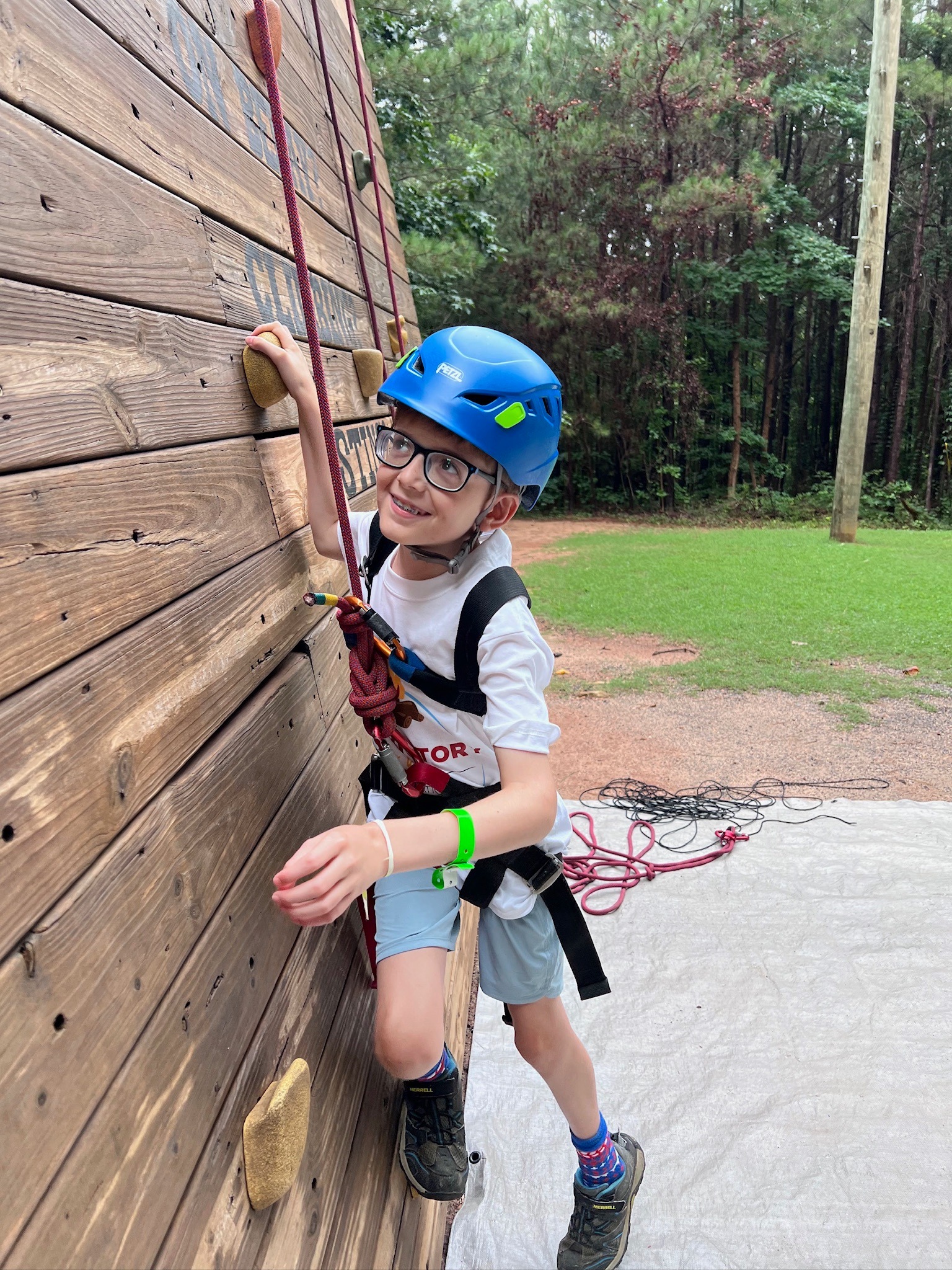 James climbing an outdoor climbing wall in a blue helmet